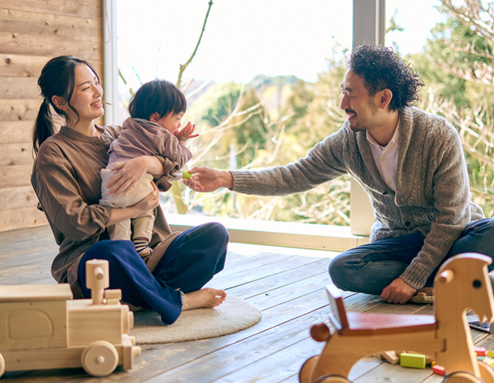 木の家で戯れる家族3人の画像