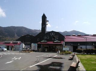 山を背景に、サイロをモチーフにした塔がある赤い屋根の酪農王国オラッチェの写真