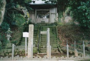 古びた木で出来た少し大きい祠の下に緑色に変色した石の階段が2列並んでいて右と左で階段の位置が上下にずれていて周りには入れないように囲いがしてある写真