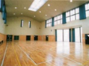 天井からすぐ下にある大きな窓から日が差し込み木目調の床に反射している様子の広々とした多目的ルームの写真