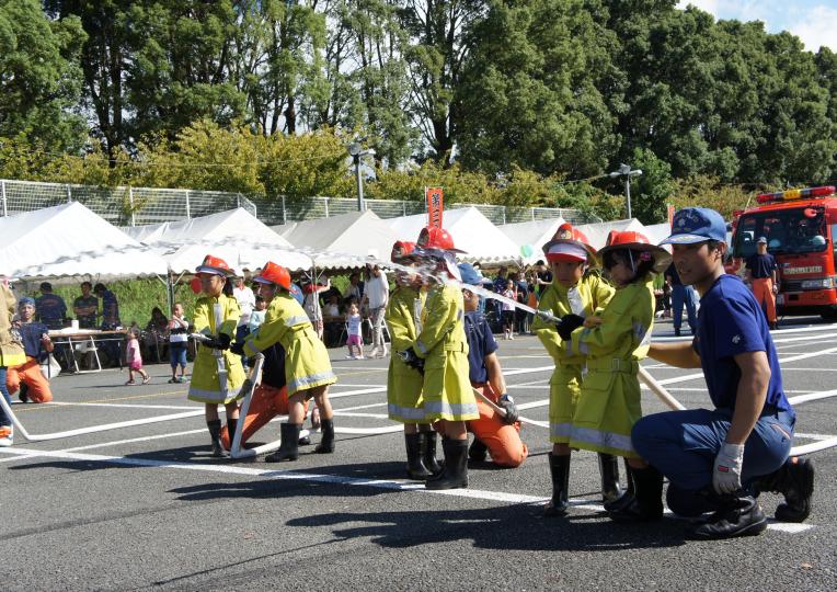 消防の装備を付けた子供たちが放水を体験している防災フェアの写真