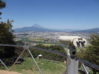 灰色っぽい双眼鏡が据え付けられている展望台から見た山々が見える景色の写真