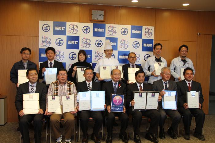 授与された認定証を手にした人たちの集合写真