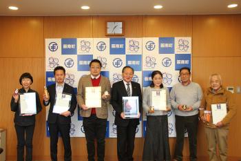 認定証や認定品を手にした人々の集合写真