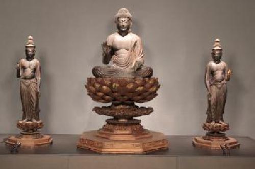 真ん中で蓮の花の台座に座り左手をひざに置き右手を挙げている阿弥陀如来と両脇侍像がその両脇に立ちそれぞれ片手をあげている様子の阿弥陀三尊像の写真